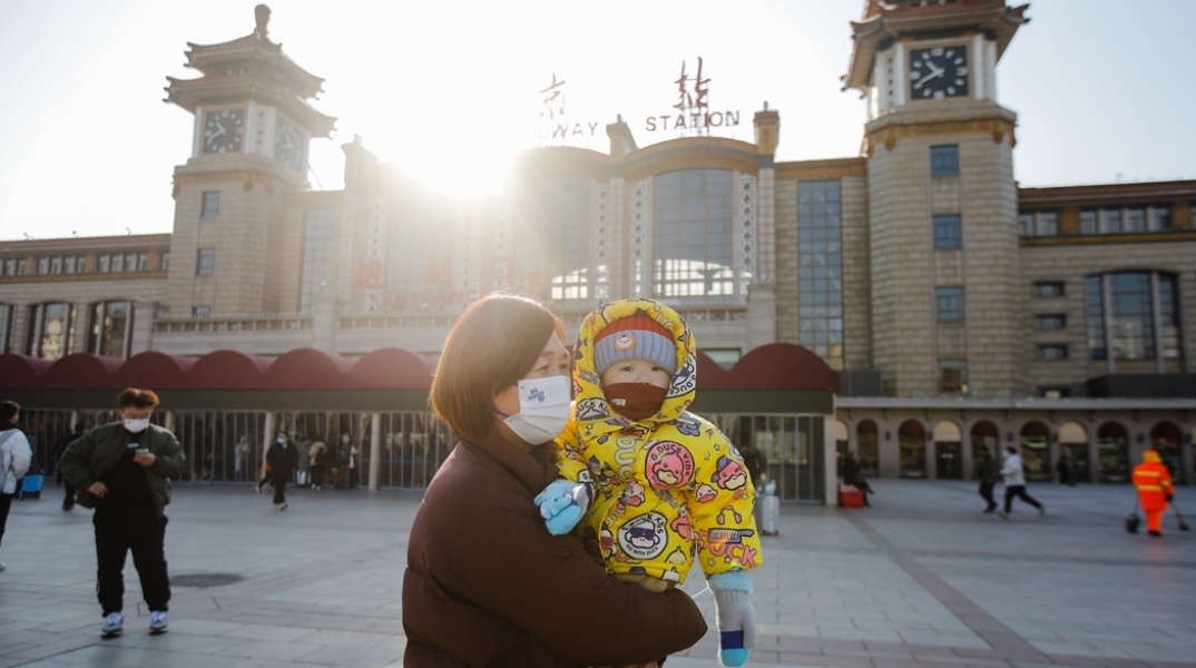 Γυναίκα με μωρό φορούν μάσκα προστασίας από τον κορωνοϊό σε πόλη της Κίνας