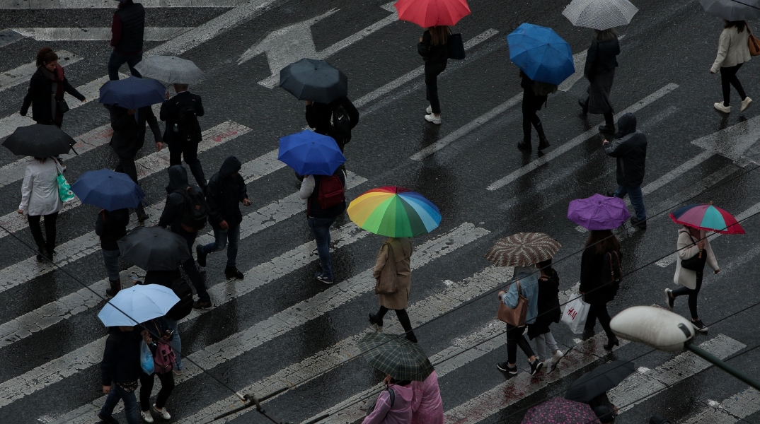 Πολίτες με ομπρέλες προστατεύονται από την καταιγίδα