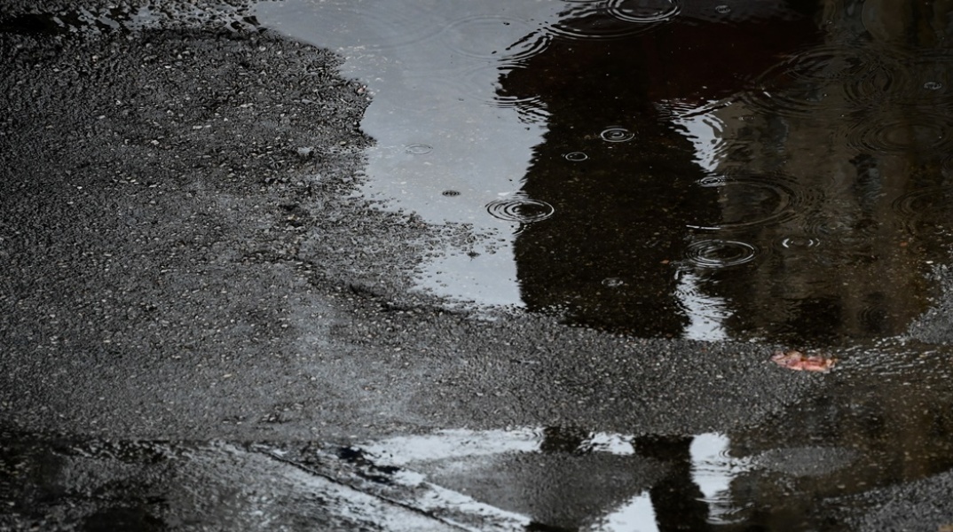 Η σκιά ατόμου με ομπρέλα σε λιμνάζοντα νερά