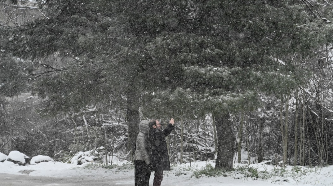 Πολίτες φωτογραφίζονται κατά τη διάρκεια χιονόπτωσης