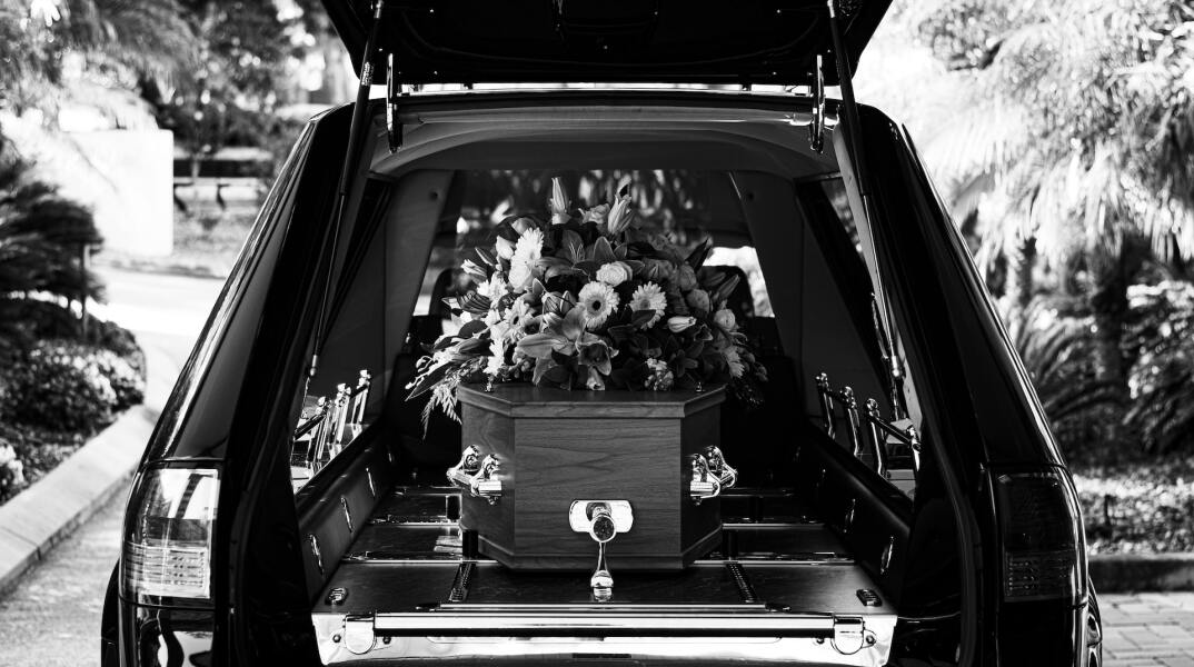 Φέρετρο με λουλούδια μέσα σε ανοιχτή νεκροφόρα