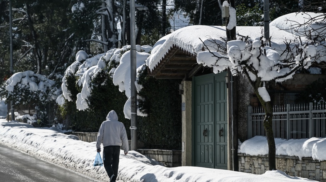 Άνδρας με σακούλα στο χέρι περπατά στον χιονισμένο Διόνυσο Αττικής