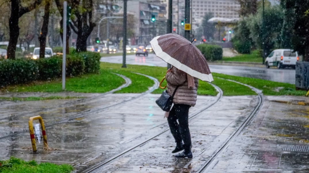 Γυναίκα με ομπρέλα περπατά σε βρεγμένο δρόμο 