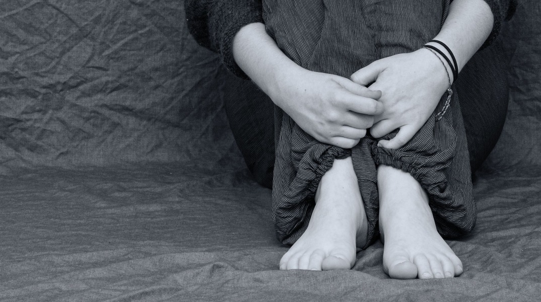 Παιδί καθισμένο με τα χέρια στα πόδια