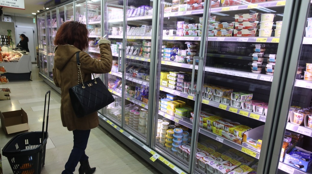 Γυναίκα μπροστά από ψυγείο σούπερ μάρκετ με γαλακτοκωμικά προϊόντα