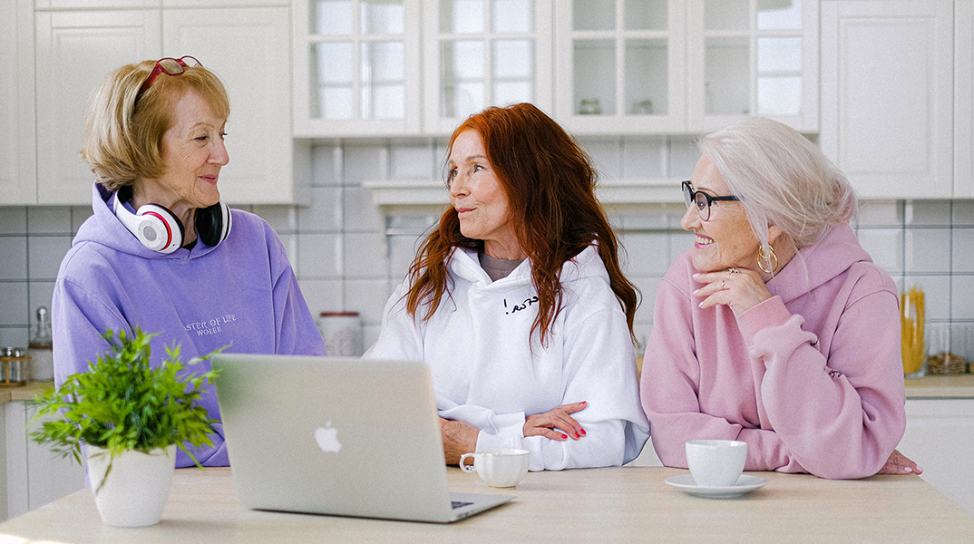 ηλικιωμένες γυναίκες στέκονται στο τραπέζι στην κουζίνα και μιλάνε
