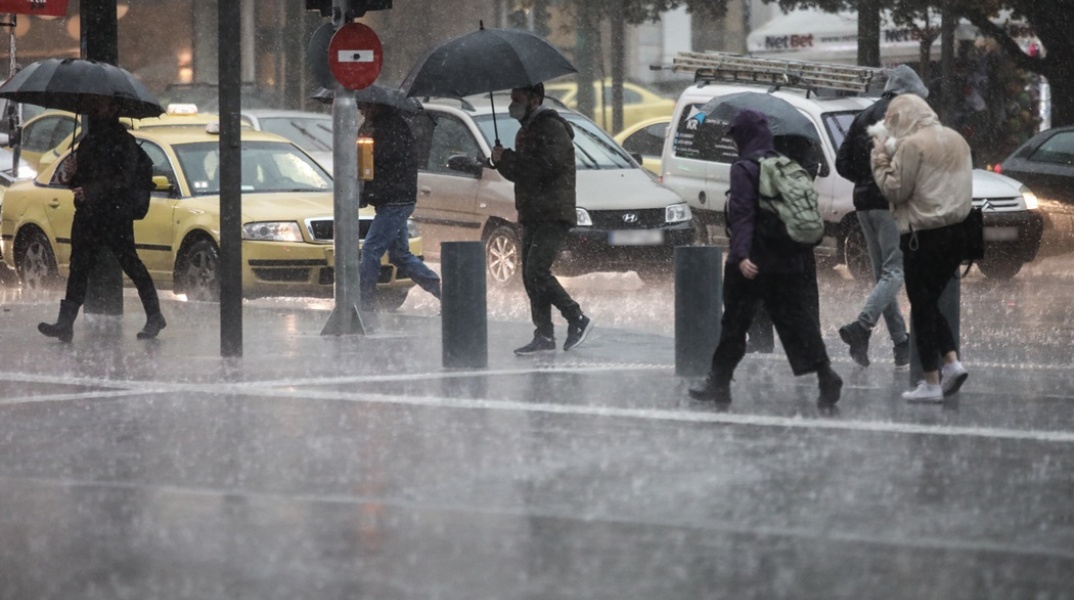 Πολίτες με ομπρέλες κατά τη διάρκεια ισχυρής καταιγίδας στο κέντρο της Αθήνας