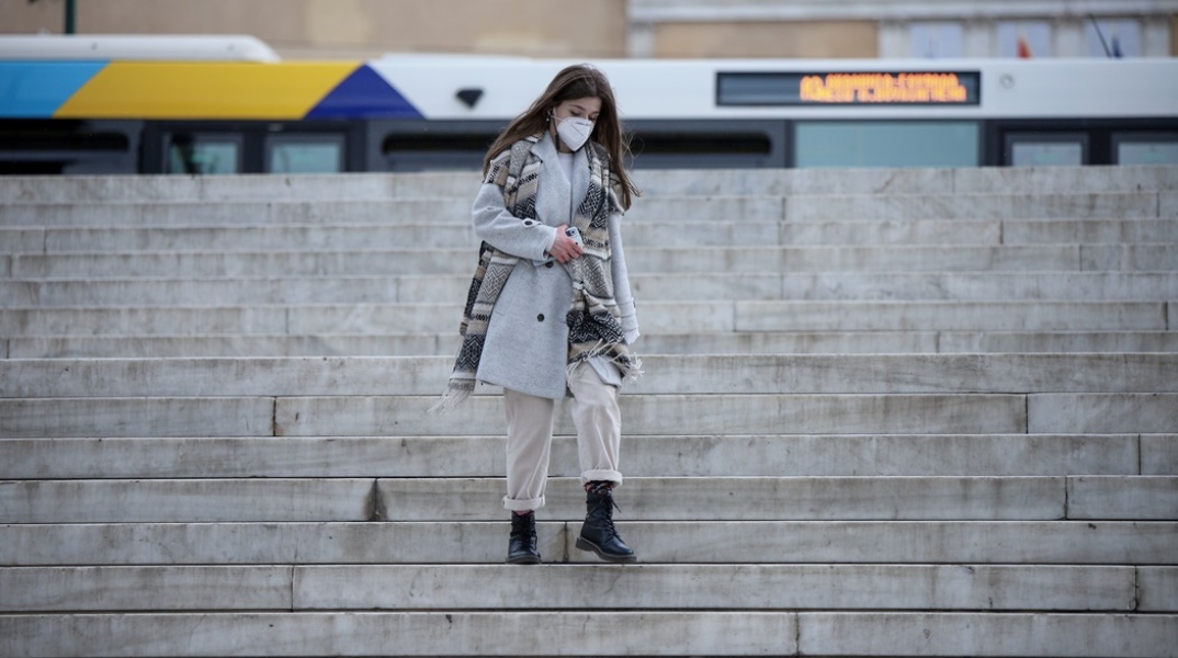 Γυναίκα κατεβαίνει τα σκαλιά της πλατείας Συντάγματος φορώντας μάσκα προστασίας από τον κορωνοϊό