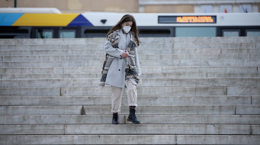Γυναίκα κατεβαίνει τα σκαλιά της πλατείας Συντάγματος φορώντας μάσκα προστασίας από τον κορωνοϊό