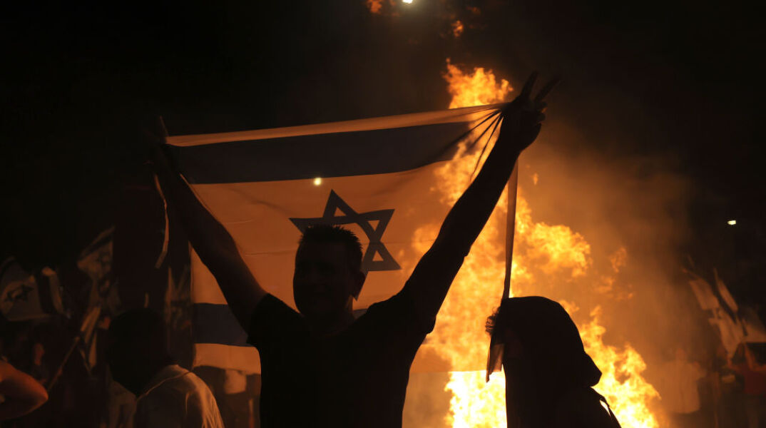 Άνδρας με σημαία του Ισραήλ διαμαρτύρεται για την αναθεώρηση του δικαστικού συστήματος