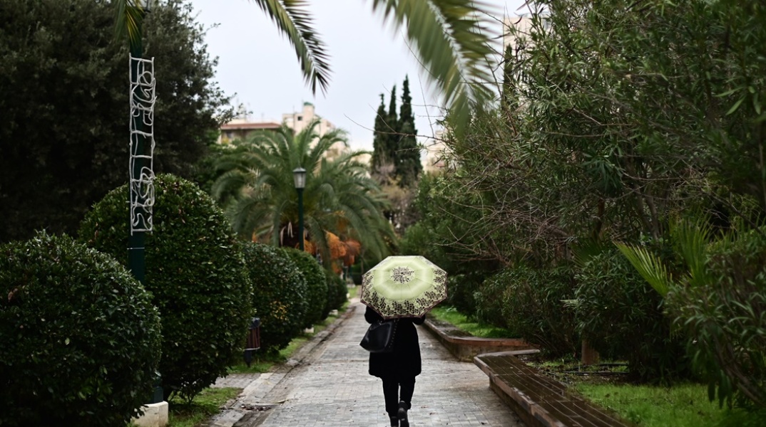 Γυναίκα με ομπρέλα περπατά στη βροχή
