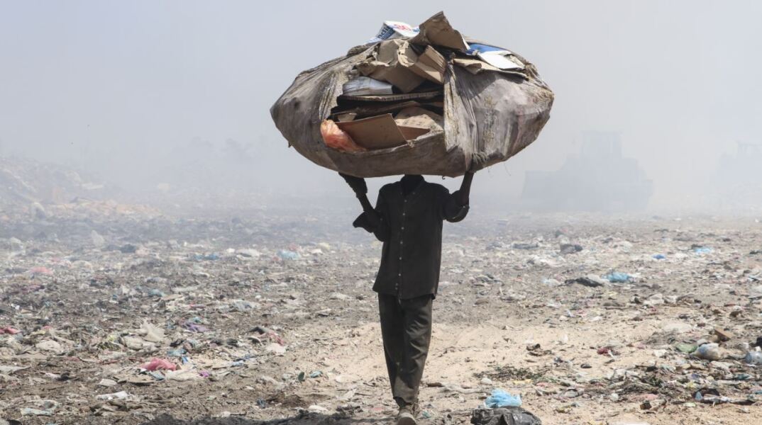 Ένας συλλέκτης σκουπιδιών μεταφέρει ανακυκλωμένα υλικά από μια χωματερή για να βγάλει τα προς το ζην στην οικογένειά του