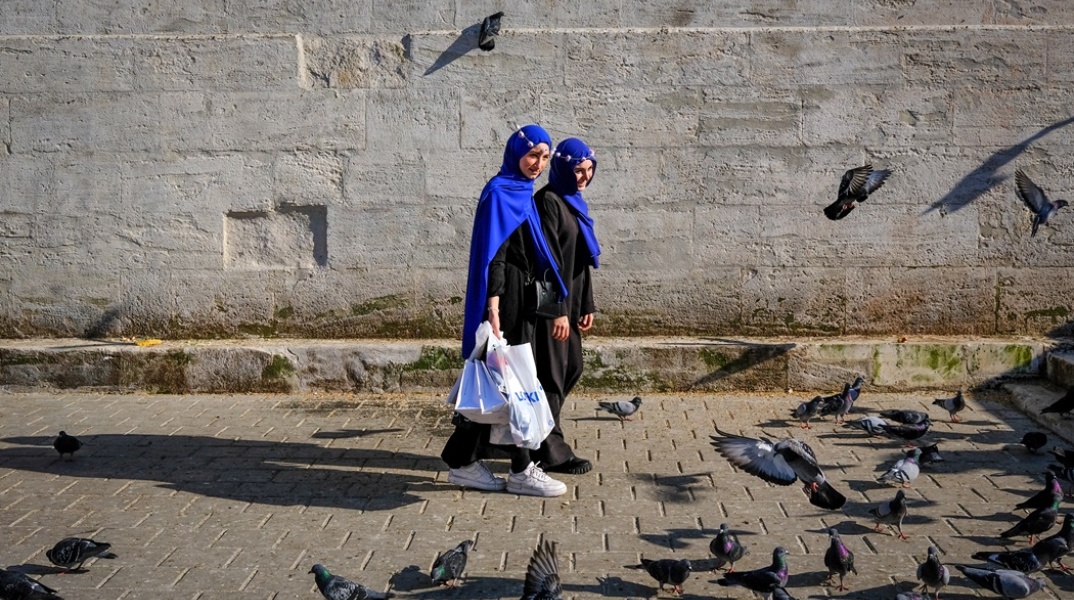 Γυναίκες περπατούν δίπλα από περιστέρια σε δρόμο στην Τουρκία