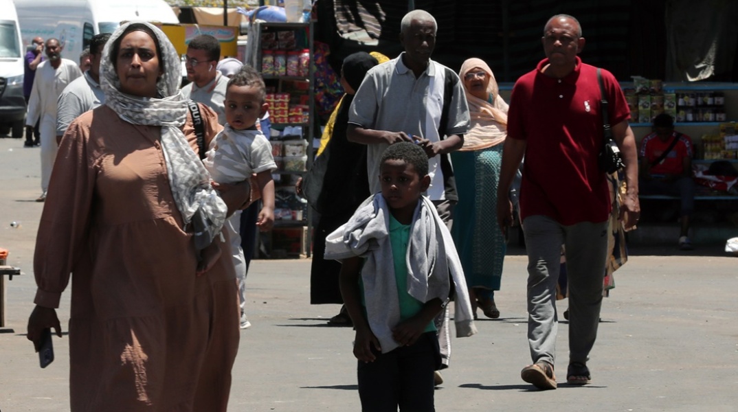 Γυναίκα με τα παιδιά της φεύγει από το Σουδάν μετά το ξέσπασμα των συρράξεων