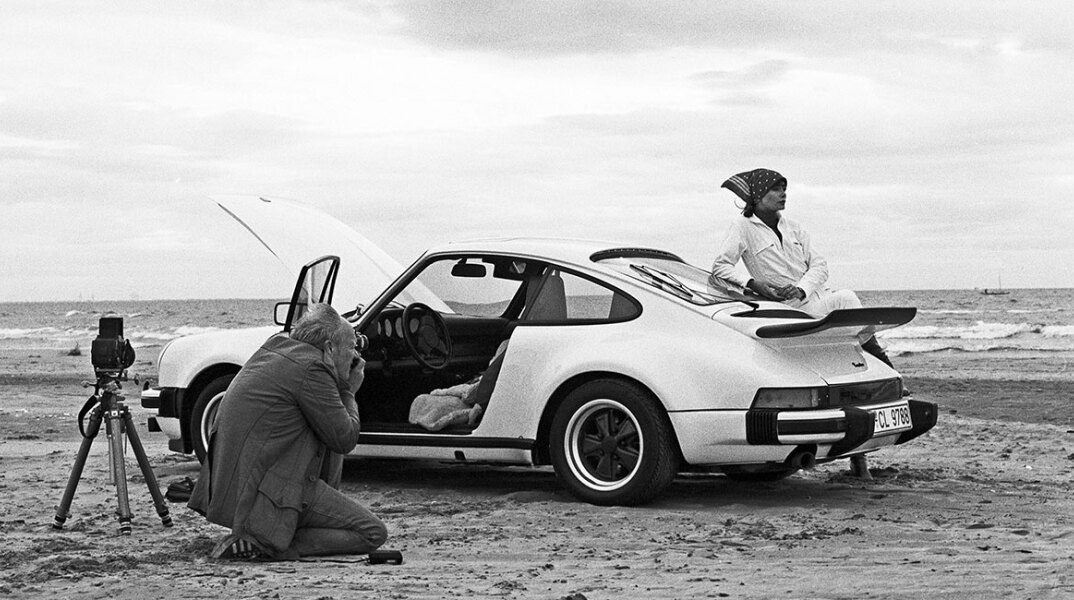 Ασπρόμαυρη φωτογραφία με γυναίκα που ποζάρει δίπλα σε Porsche