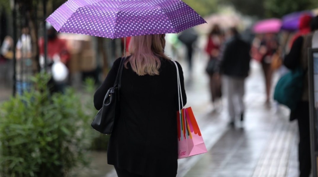 Γυναίκα με ομπρέλα προστατεύεται από βροχόπτωση