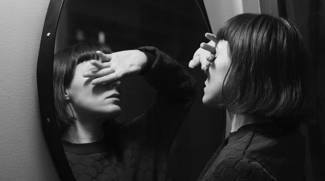 Γυναίκα καλύπτει τα μάτια της μπροστά σε καθρέφτη