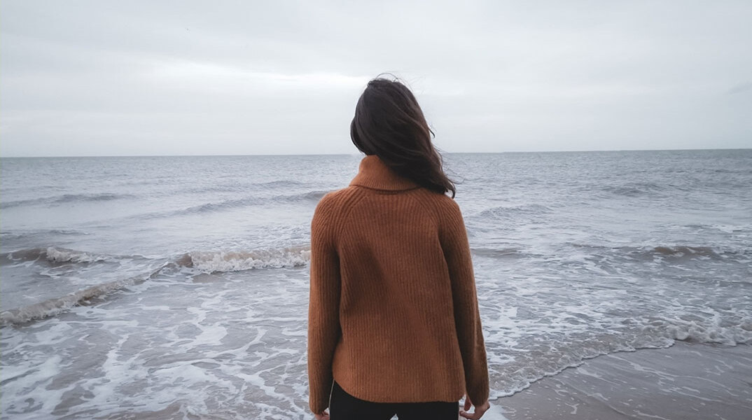 Κοπέλα με γυρισμένη πλάτη κοιτάζει τη θάλασσα