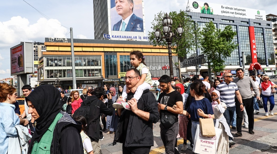 Πολίτες περπατούν μπροστά από αφίσα του Ρετζέπ Ταγίπ Ερντογάν - Σήμερα οι δεύτερες εκλογές στην Τουρκία