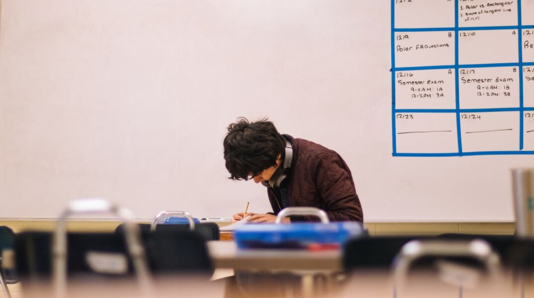 Μαθητής μελετά και γράφει, κάνοντας την προετοιμασία του για τις εξετάσεις εισαγωγής σε πανεπιστήμιο