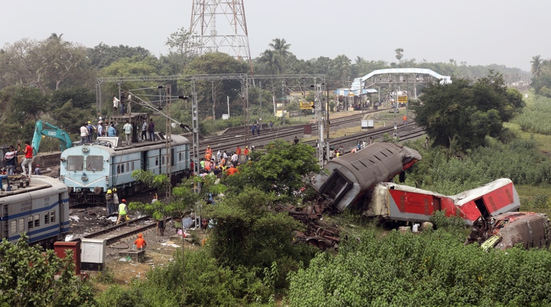 Χαλάσματα και εργάτες για να τα απομακρύνουν από το σημείο όπου καταγράφηκε το σιδηροδρομικό δυστύχημα στην Ινδία