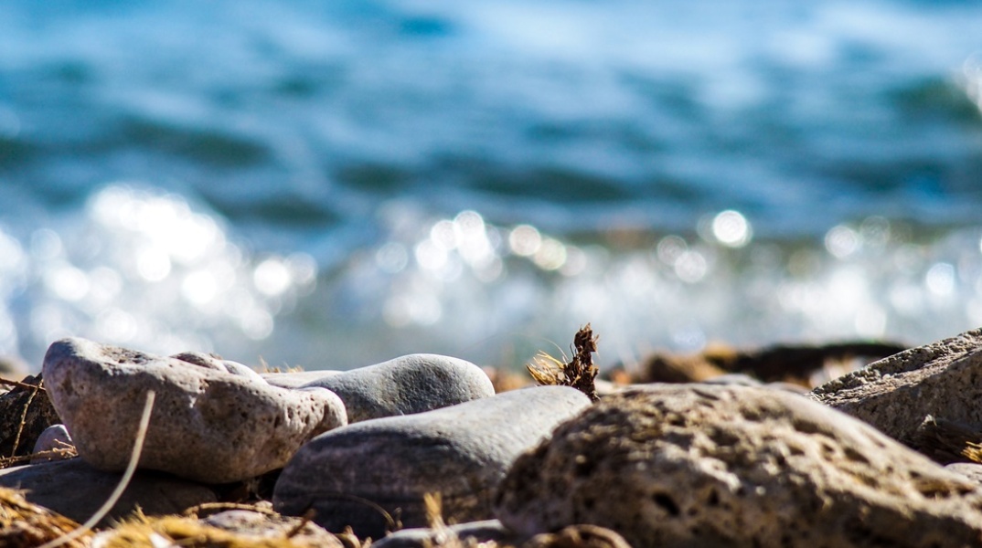 Βότσαλα λουσμένα με το φως του ήλιου στην ακροθαλασσιά