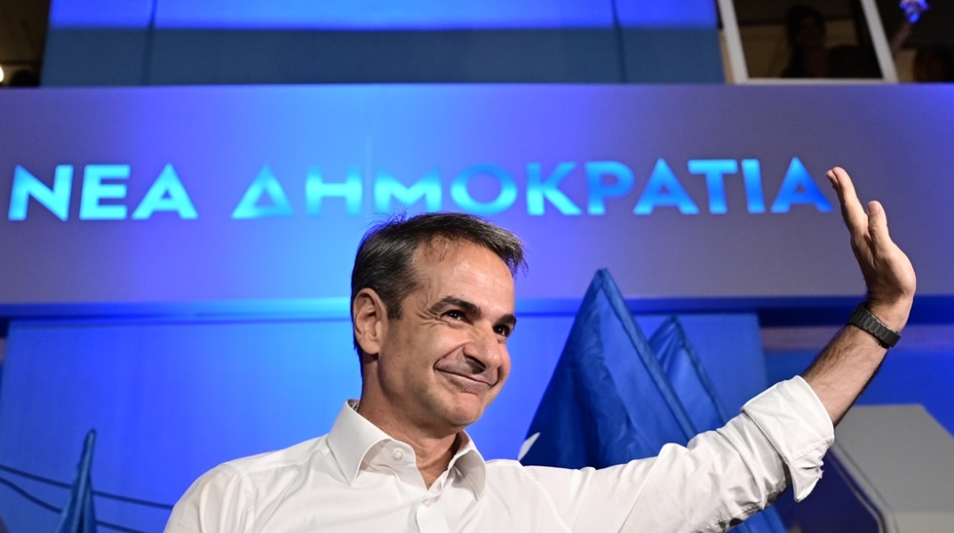 Ο Κυριάκος Μητσοτάκης με υψωμένο το χέρι χαιρετά τους φίλους και τα στελέχη της ΝΔ που συγκεντρώθηκαν έξω από τα γραφεία του κόμματος στην Πειραιώς μετά το εκλογικό αποτέλεσμα