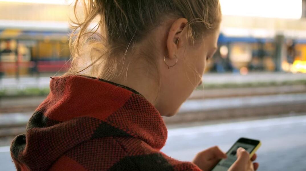 Νεαρή κοπέλα χρησιμοποιεί κινητό