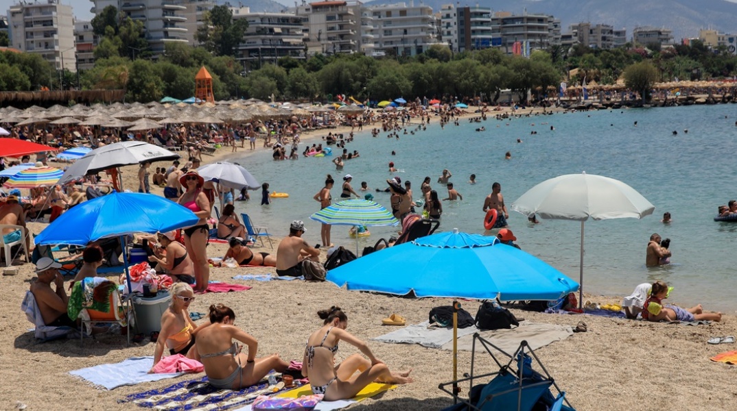 Λουόμενοι σε παραλία απολαμβάνουν ήλιο και θάλασσα