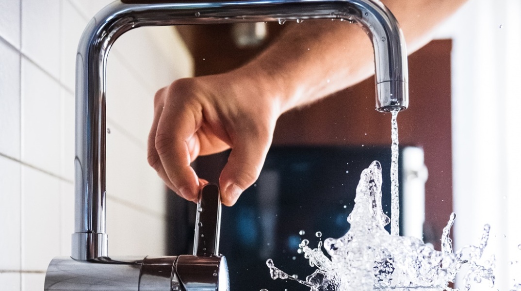 Νερό τρέχει από τη βρύση μέσα σε ποτήρι με φόρα- Ένα χέρι ανοίγει τη βρύση