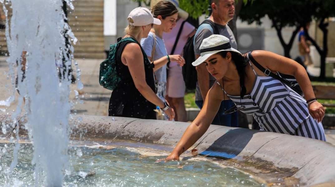 Γυναίκα δροσίζει τα χέρια της λόγω της ανυπόφορης ζέστης στο σιντριβάνι της πλατεία Συντάγματος