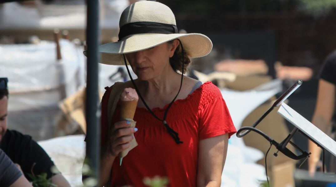 Γυναίκα απολαμβάνει ένα χωνάκι παγωτό στην προσπάθειά της να δροσιστεί
