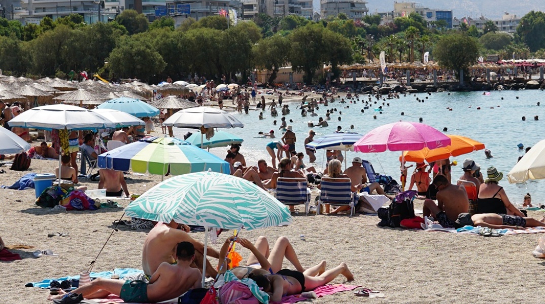 Λουόμενοι σε παραλία απολαμβάνουν ήλιο και θάλασσα