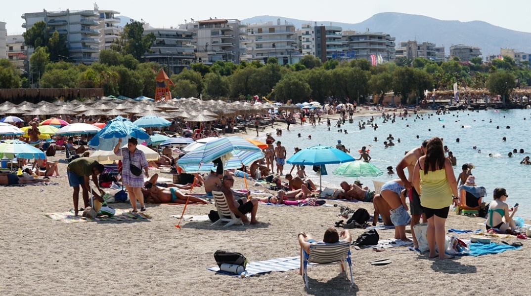 Λουόμενοι σε παραλία απολαμβάνουν ήλιο και θάλασσα