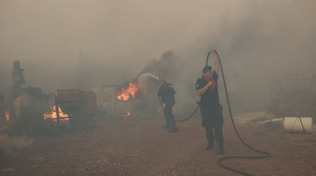 Πυροσβέστες και εθελοντές με μάνικα στα χέρια επιχειρούν για την κατάσβεση πυρκαγιάς