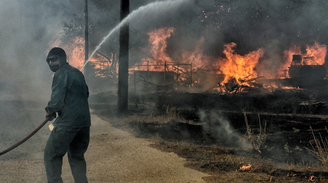 Άνδρας με μάνικα επιχειρεί για την κατάσβεση φωτιάς στο Λουτράκι