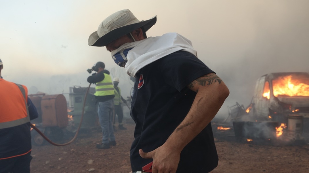 Άνδρας που βοηθά στην κατάσβεση φωτιάς στην ανατολική Αττική φορά στο πρόσωπό του μπλούζα για να προστατευτεί 