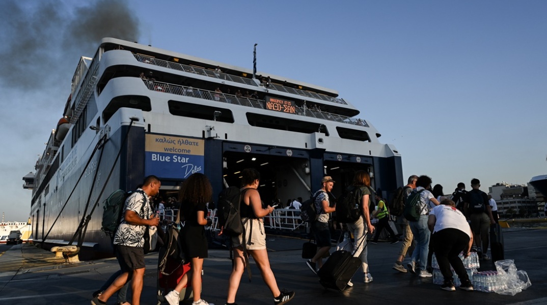 Πολίτες με βαλίτσες ετοιμάζονται για την επιβίβασή του σε πλοίο στο λιμάνι του Πειραιά