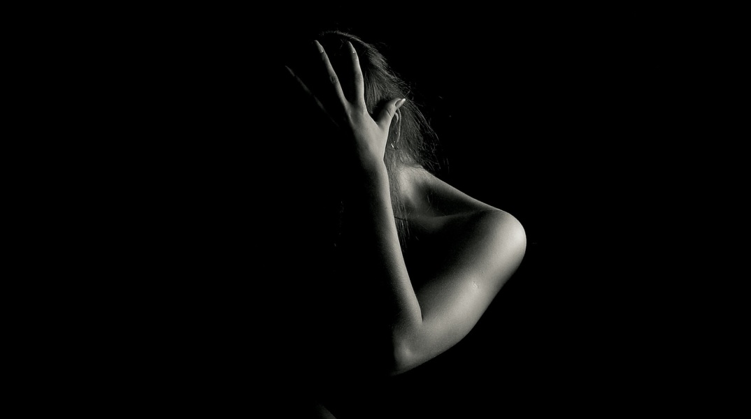 Γυναίκα με κρυμμένο το πρόσωπό της και το χέρι της στο κεφάλι σε ασπρόμαυρη φωτογραφία