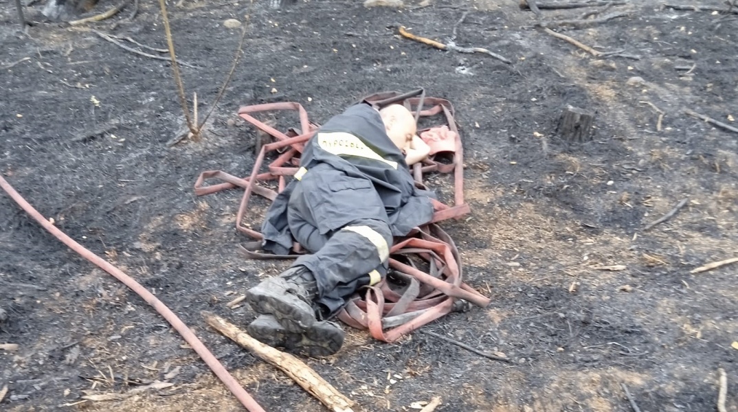 Πυροσβέστης ξαπλωμένος σε καμένη γη μετά από φωτιά στον Έβρο