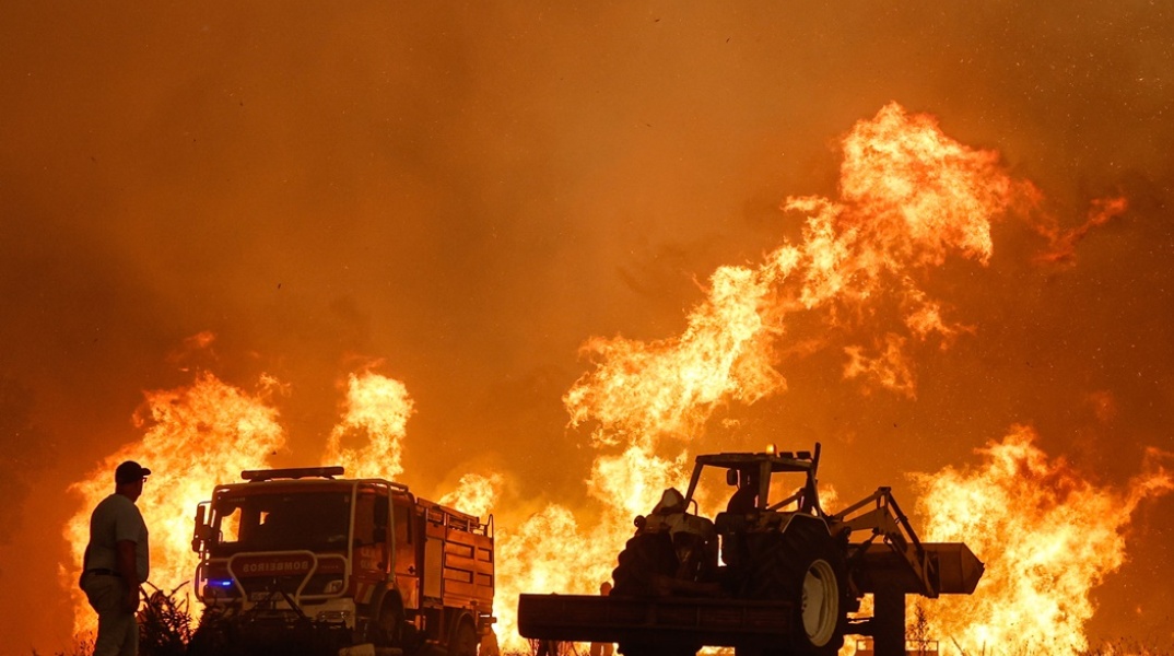 Φωτιά στην Πορτογαλία και οι σκιές ατόμου και οχημάτων με φόντο τις φλόγες