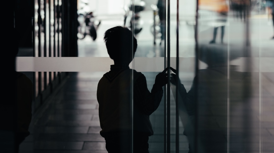 Παιδί σε σκοτεινό διάδρομο φαίνεται να φοβάται να βγει στο φως - Εικόνα που παραπέμπει σε κακοποίηση και bullying