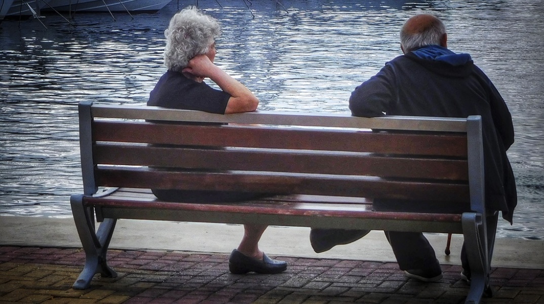 Συνταξιούχοι κάθονται σε παγκάκι κοντά σε μαρίνα