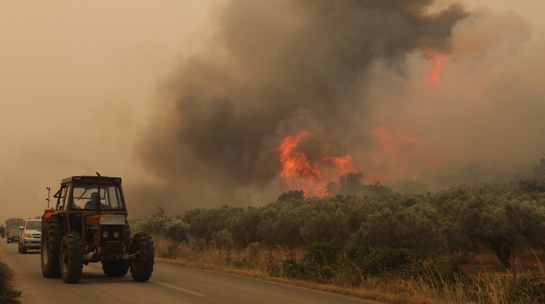 Τρακτέρ περνά σε δρόμο όπου δίπλα καίει η φωτιά στην Αλεξανδρούπολη