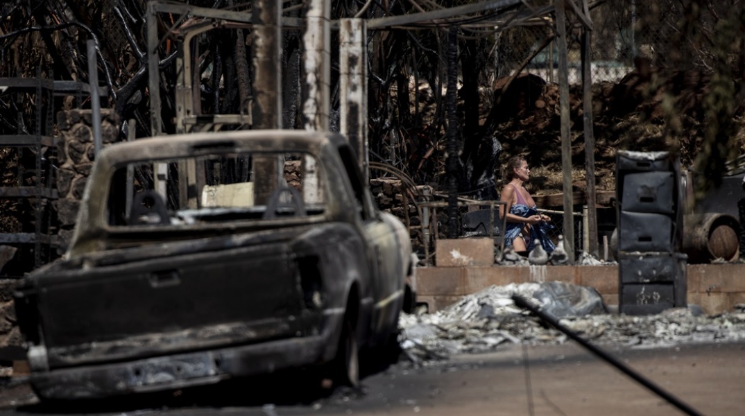 Καμένα αυτοκίνητα και σπίτια από τις φονικές πυρκαγιές στο Μάουι της Χαβάης και γυναίκα στο σημείο