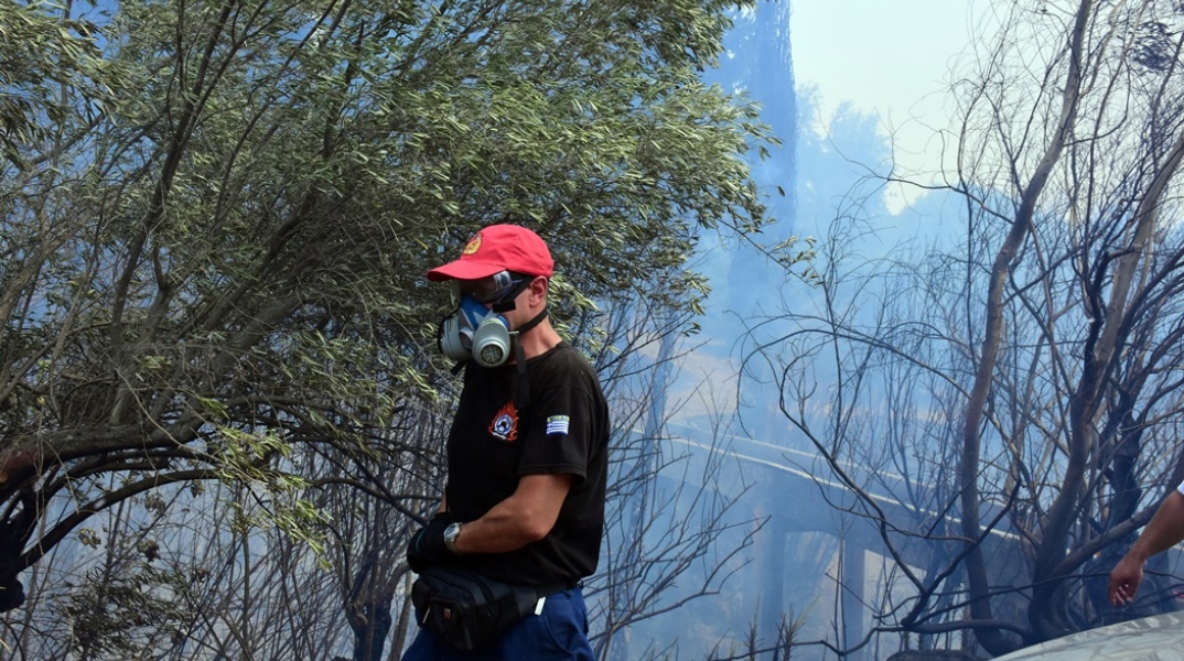 Πυροσβέστης με μάσκα και τη μάνικα ανά χείρας