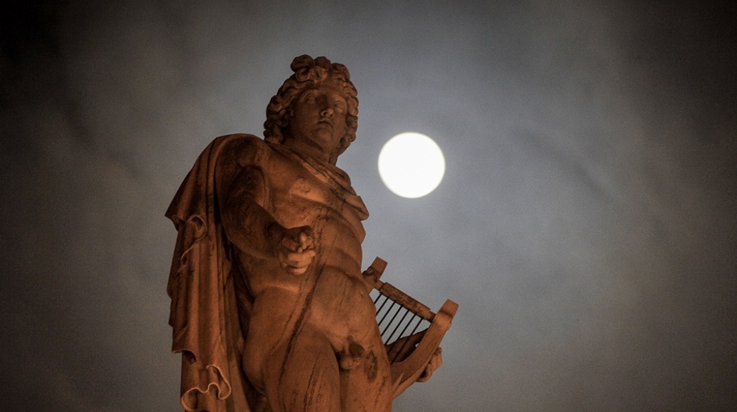 Μπλε φεγγάρι φωτίζει τον ουρανό πίσω από άγαλμα