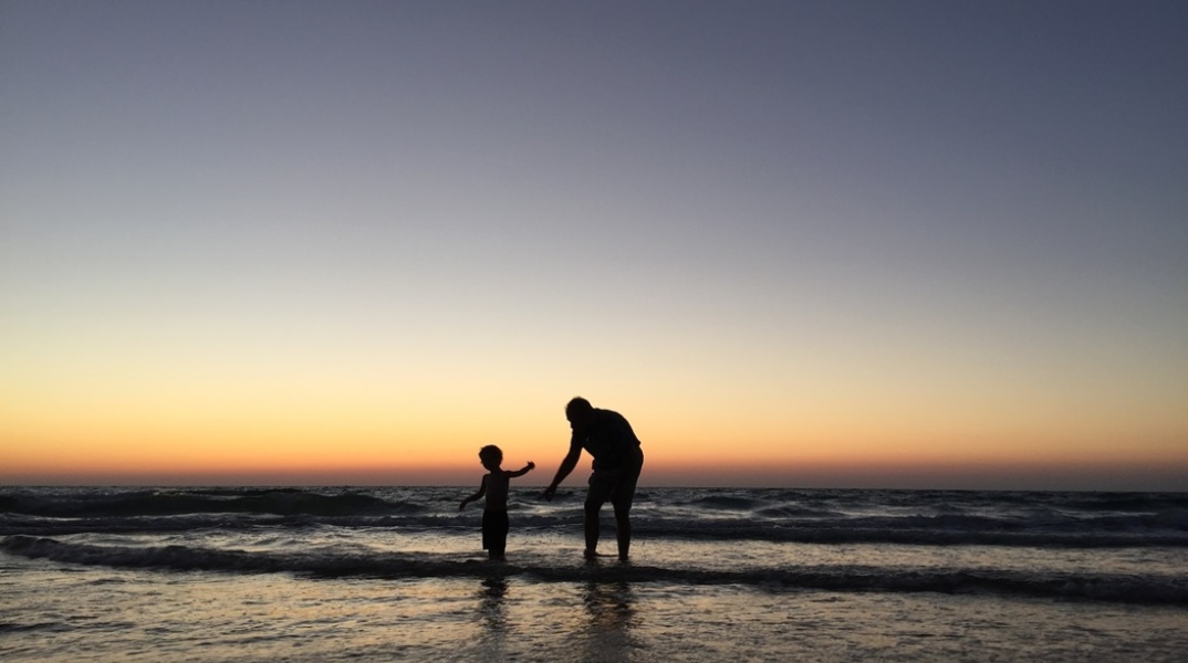 Παιδί παίζει με τον μπαμπά του στην ακροθαλασσιά