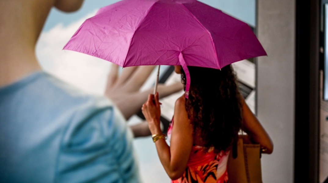 Γυναίκα κρατά ομπρέλα για να προστατευτεί από τη βροχή