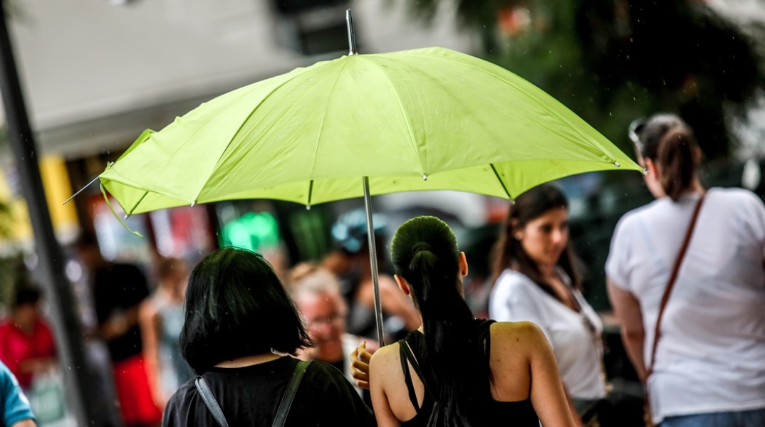 Γυναίκα με ομπρέλα προστατεύεται από τη βροχή
